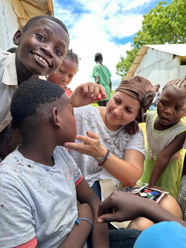 A volunteer paints a child’s face during camp