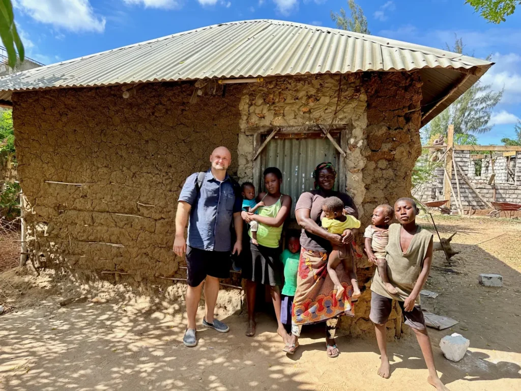 Dzianis Laptseikin with a large family outside their mud-walled home in Kenya