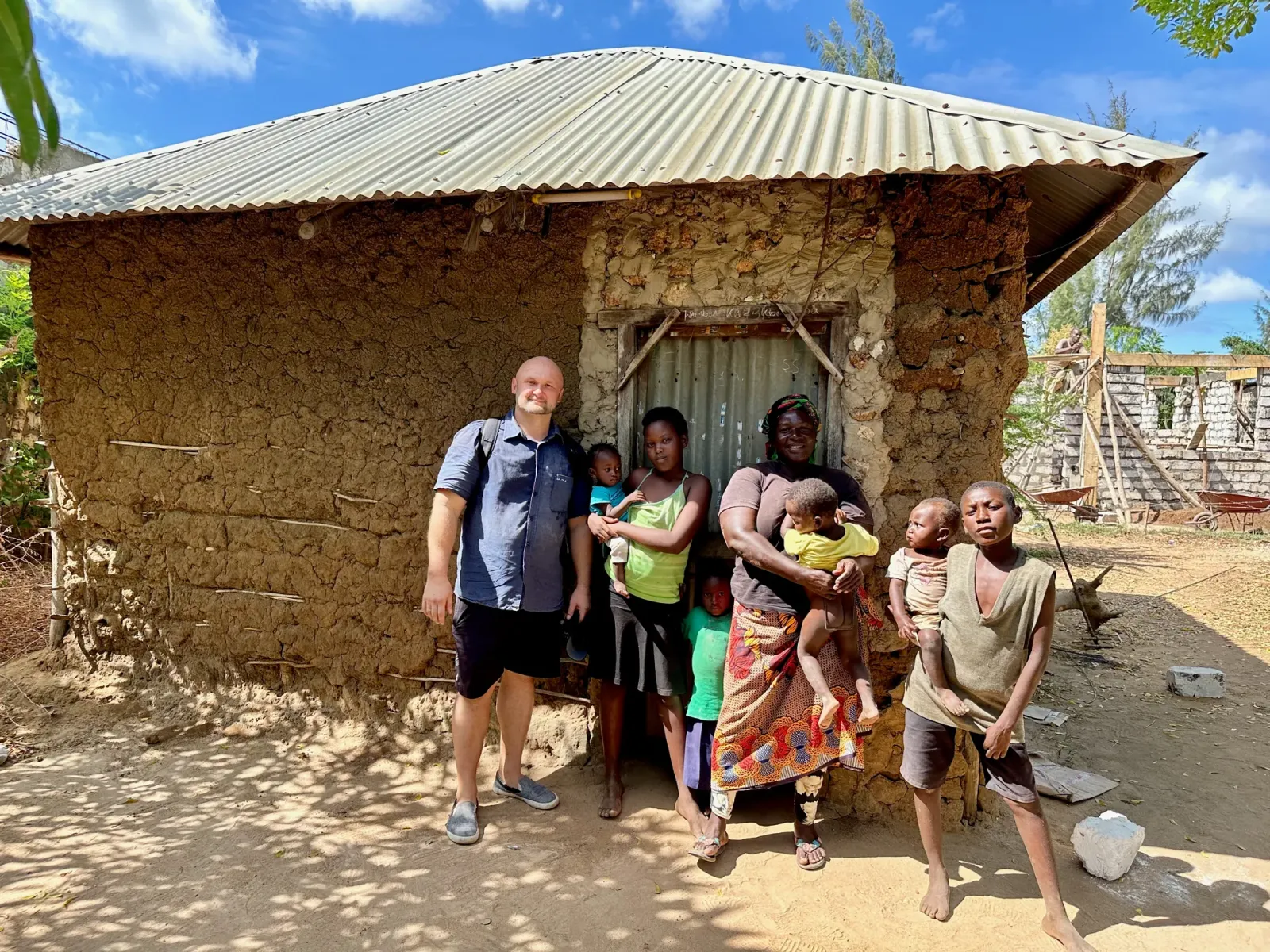 Dzianis Laptseikin with a large family outside their mud-walled home in Kenya