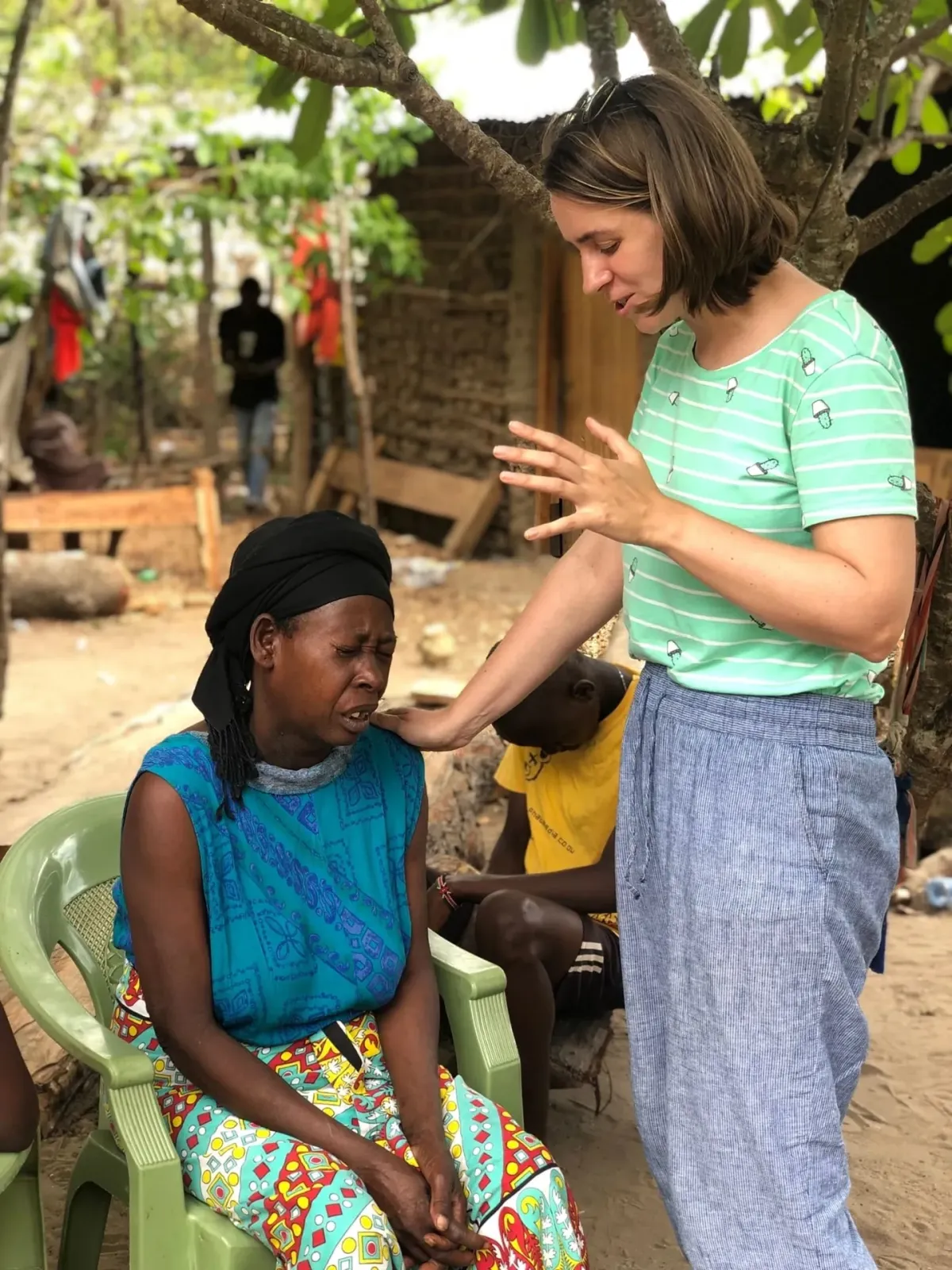 Volunteer praying for a woman and her children outside their home in Kenya