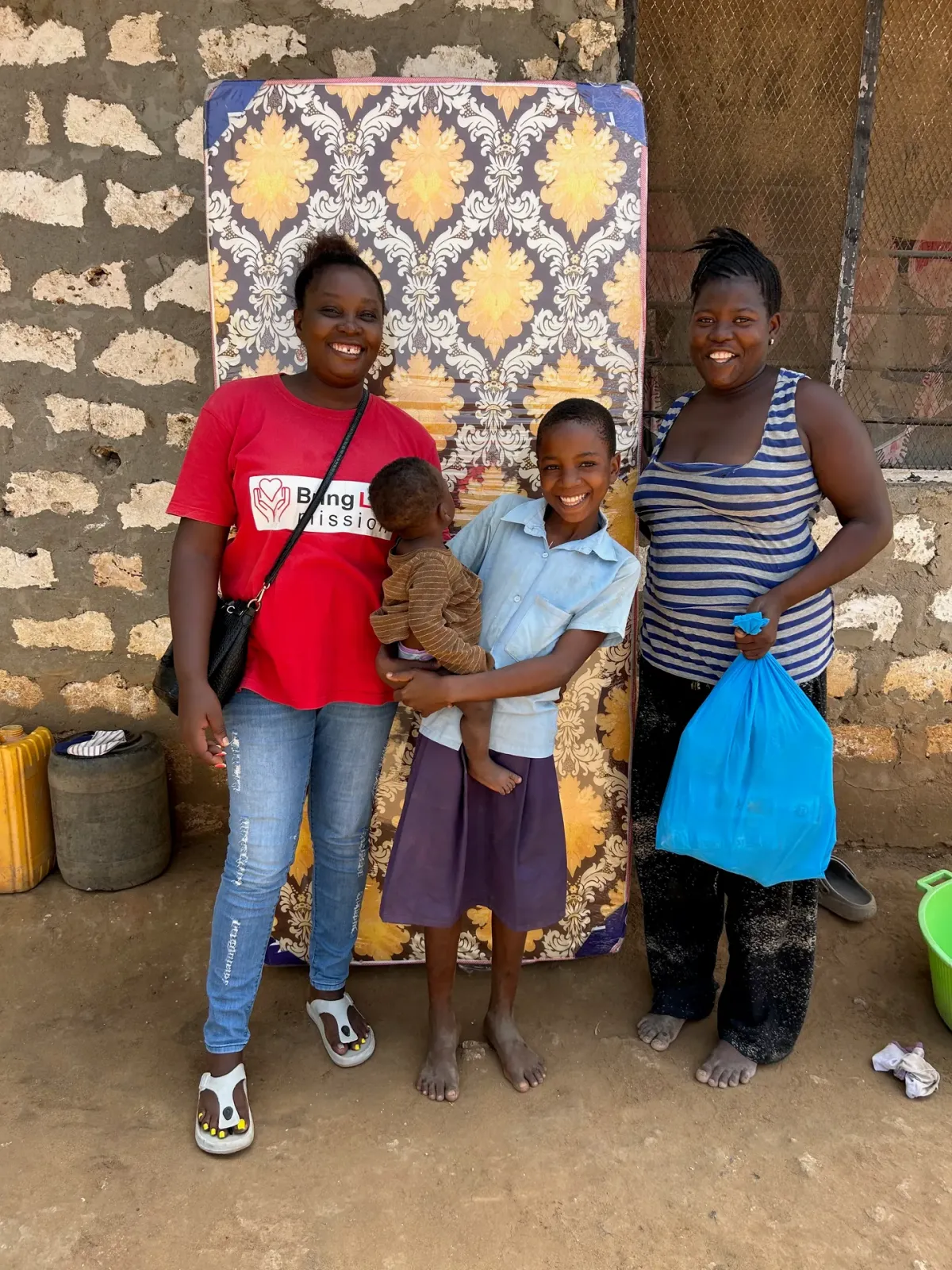 Caroline Njue handing a mattress and groceries to a Kenyan family