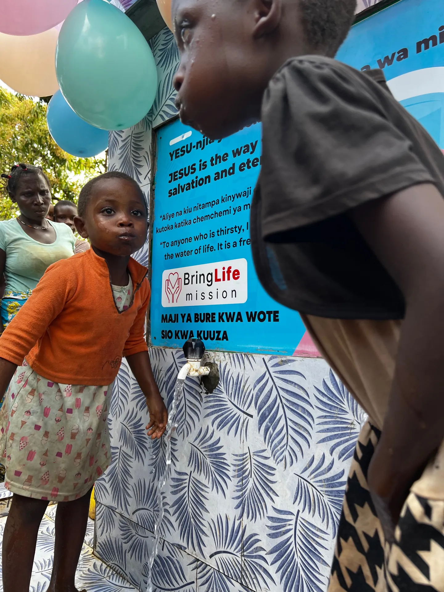 Children drink and fill containers from the faucets of a new well