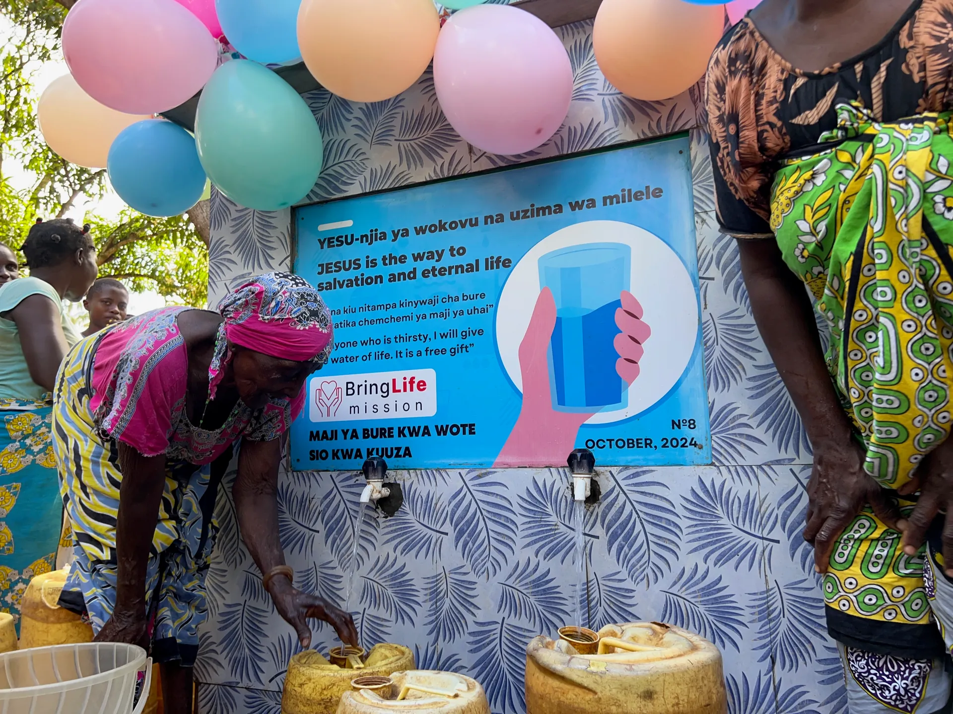 Women collect clean water during a well-opening celebration