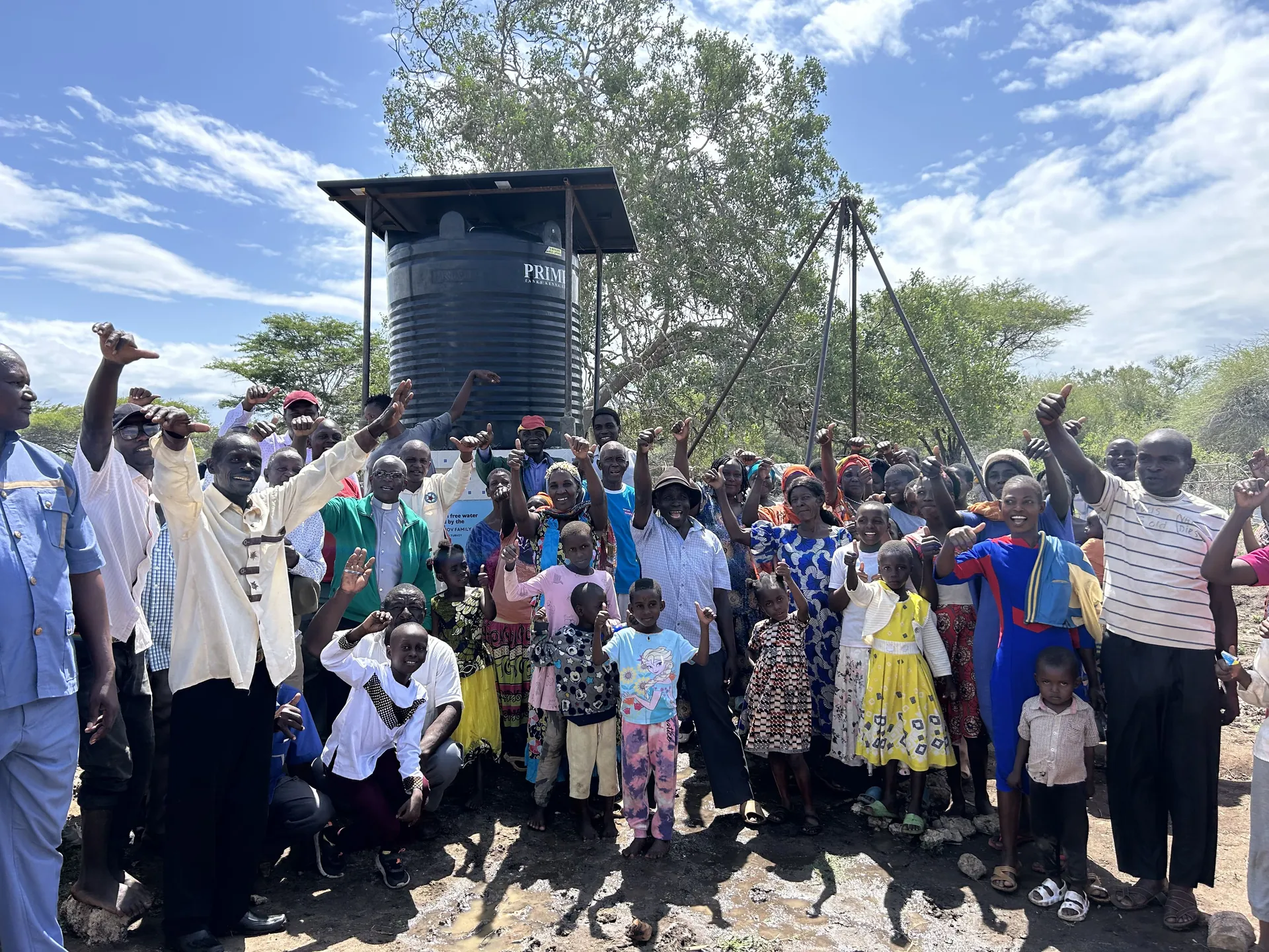 Residents celebrate beside a new well and drilling rig