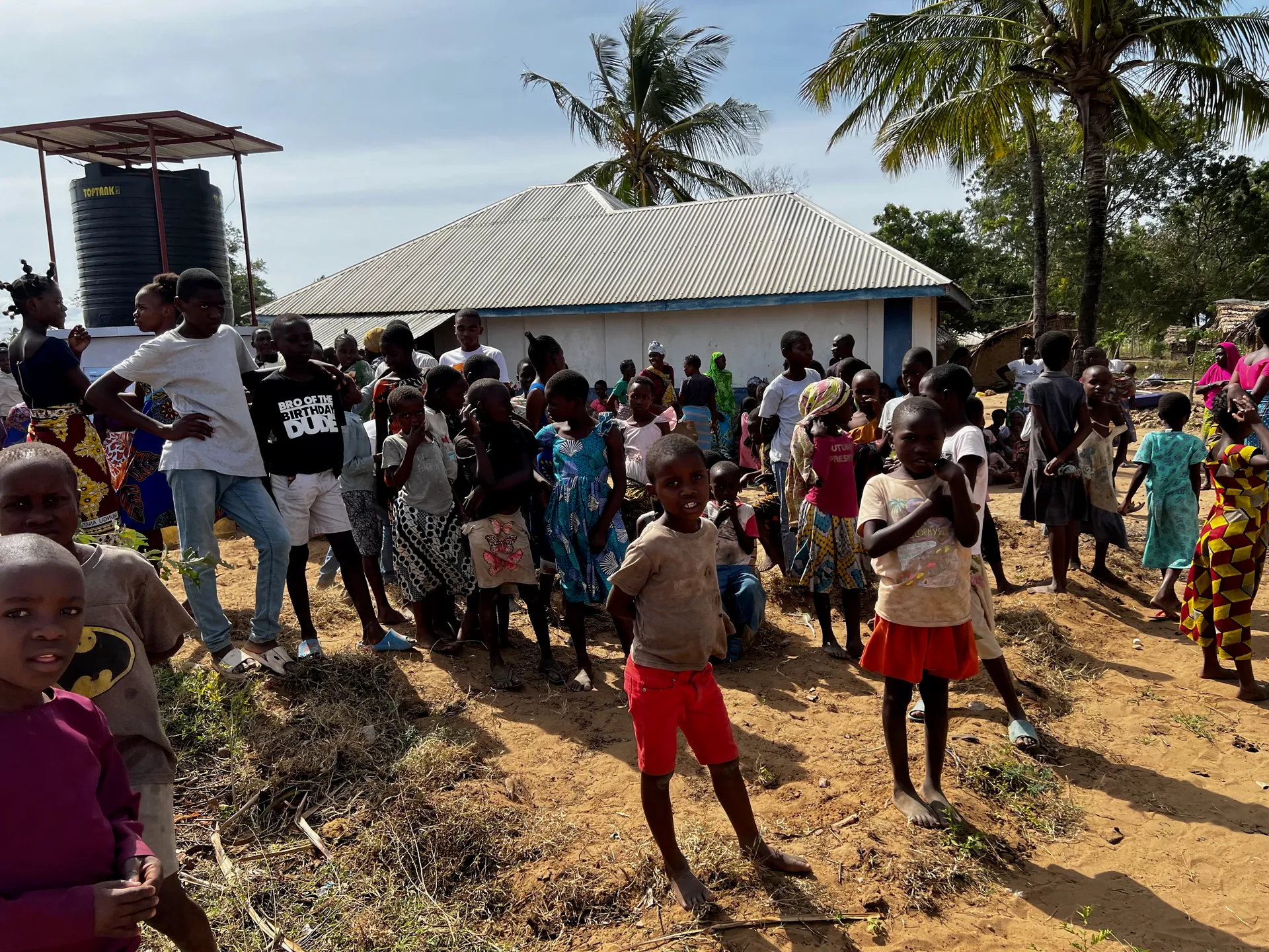 A large crowd waits for the first water at a village well opening