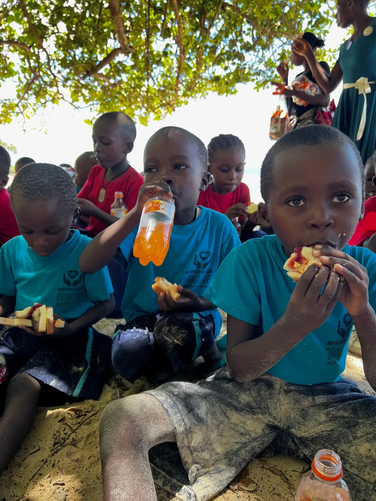Children drinking juice and having snacks in the shade after swimming