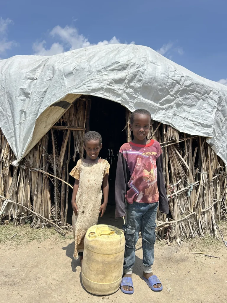 Two children outside a fragile home in Tana River County, where clean water is urgently needed