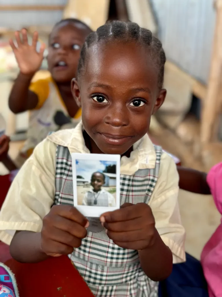 Девочка показывает свой снимок Polaroid — первую собственную фотографию