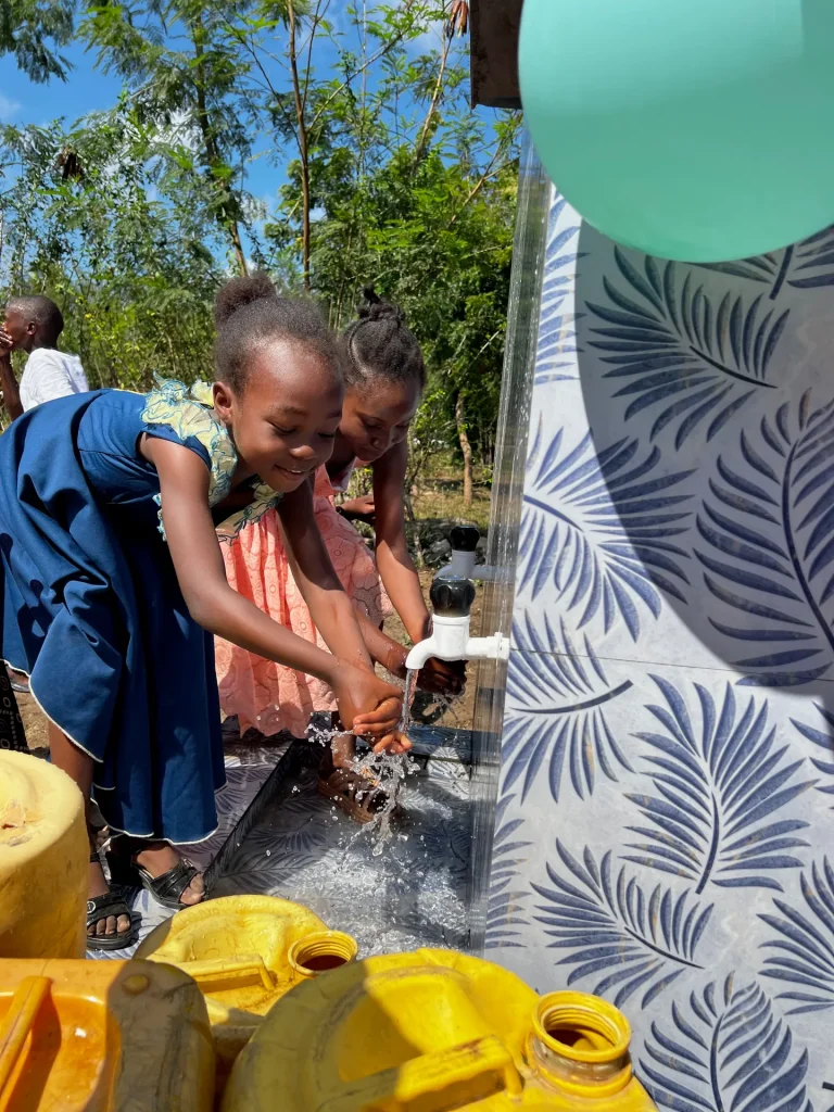 Children and residents wash with clean water at a new well
