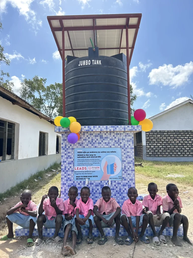 Children gather at a new Bring Life Mission water well on school grounds